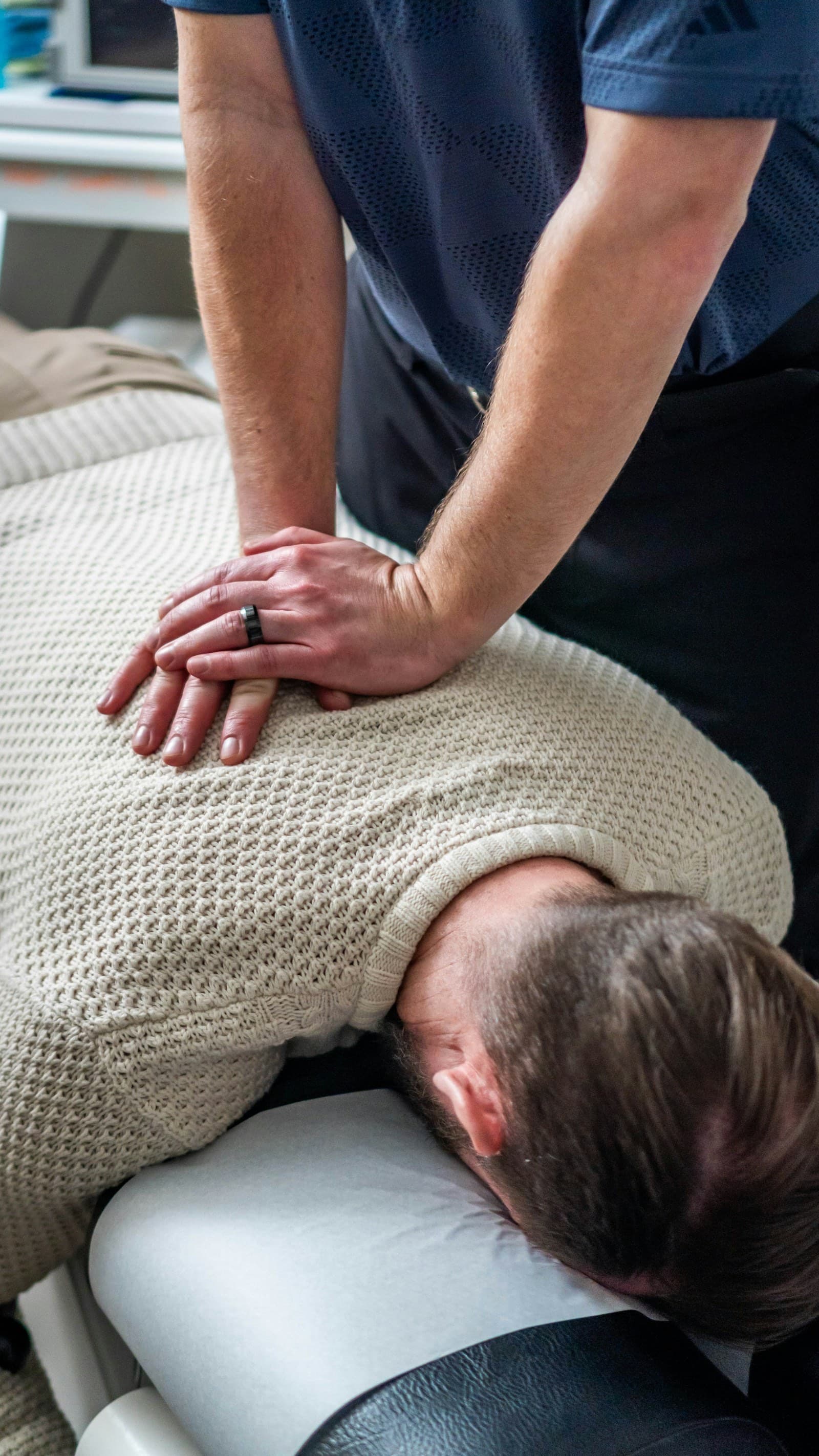 Chiropractor performing a spinal adjustment on a patient during an in-office treatment session