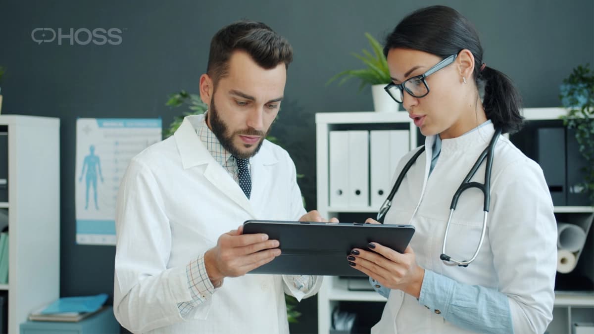 Two healthcare professionals reviewing patient data on a tablet for remote patient monitoring.
